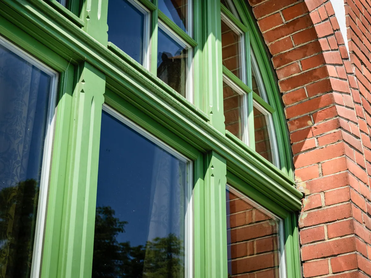 Detail eines grünen Bogenfensters mit profilierten Kämpfern